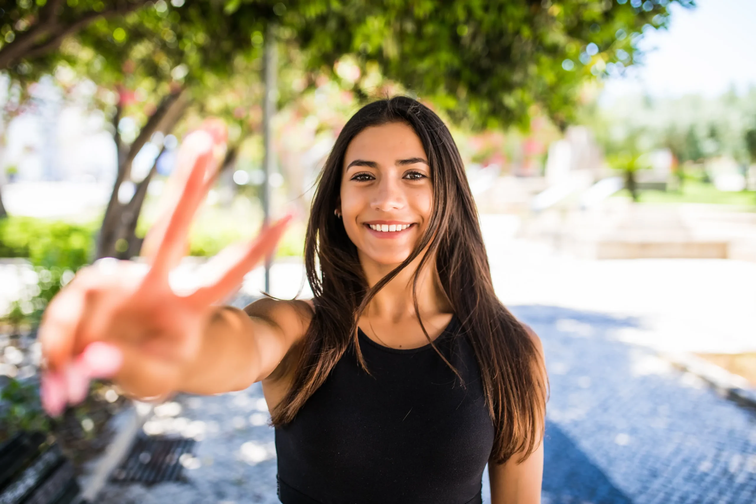 young-latin-woman-with-peace-gesture-standing-street